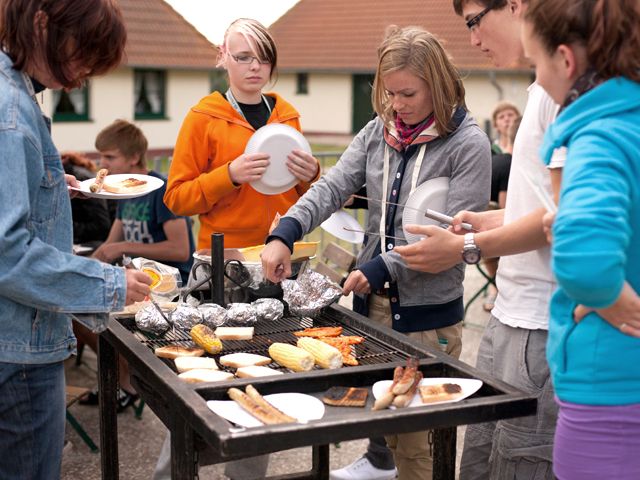 Schülerinnen und Schüler beim Grillen am Grillabend im Jugendtours-Feriendorf Ummanz – Unterkunft auf Rügen an der Ostsee